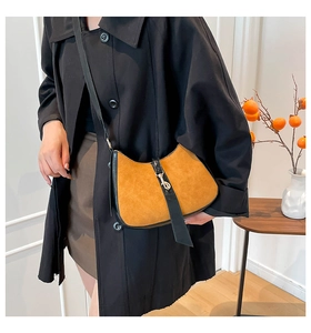 Detail of vintage suede bag with black trim and metal hook closure on shoulder