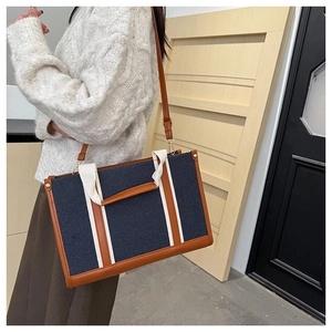 Detail of navy canvas tote with brown leather trim and white straps on a model