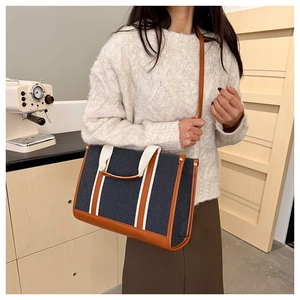 Detail view of canvas tote bag with leather trim and stylish webbing straps