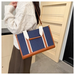 Detail showing deep blue canvas tote with brown leather trim and white woven handles