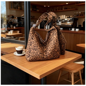 Detail of leopard print tote bag on a cafe table showing rich faux suede texture