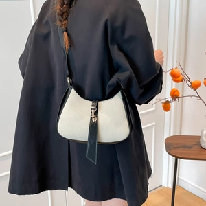 Chic beige and black contrast hobo bag with metal piston clasp shown on model
