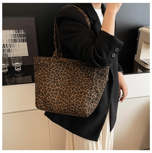 Detail showing high-capacity leopard print tote bag worn on shoulder by model in studio