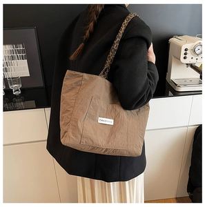 Detail of khaki tote bag with leopard print strap and brand label on front pocket