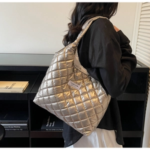 Detail of silver quilted puffer tote bag with letter label and chic rhombic texture