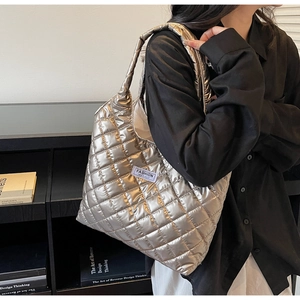 Detail of silver metallic quilted puffer tote bag on shoulder with fashion instinct label