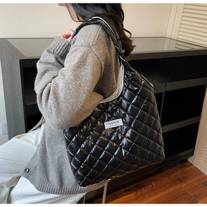 Detailed close-up of a black quilted shoulder bag with Fashion Instinct label and glossy finish