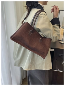 Détail d'un grand sac cabas en daim marron foncé avec de fines bretelles en cuir