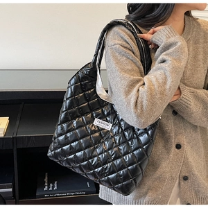 Close-up of quilted black puffer tote bag with fashion instinct label worn by a model
