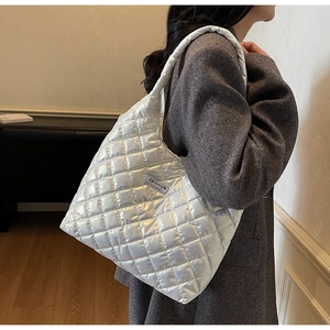 Detail view of a white quilted puffer tote bag with Fashion Instinct label on grey coat