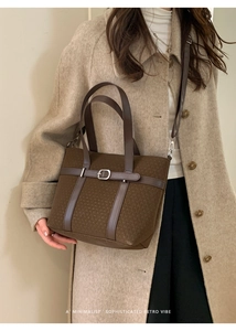 Detail of retro woven tote bag in brown fabric with leather handles on a wool coat