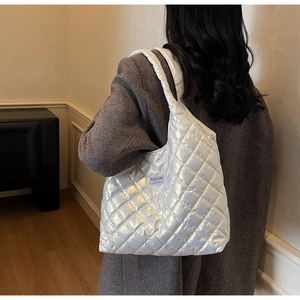 Detailed view of white quilted bucket bag with iridescent finish and fashion label