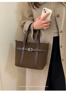 Detail view of large coffee brown tote bag with leather straps and silver metal buckle