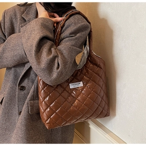 Detail der dunkelbraunen gesteppten Tragetasche mit Fashion-Label und glänzender Oberfläche