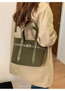 Olive green woven tote bag with silver buckle worn by a model in a minimalist setting