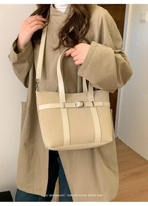 Detail of beige tote bag with textured fabric, leather accents and metallic buckle