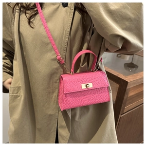 Pink mini crossbody bag with woven texture, golden twist lock and top handle detail