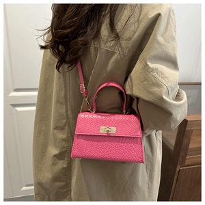 Detailed close-up of pink textured handbag with gold twist lock on a khaki trench coat