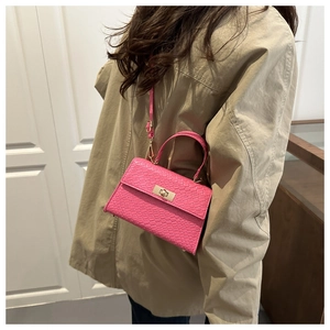 Détail du petit sac rose motif crocodile avec boucle dorée porté par un mannequin