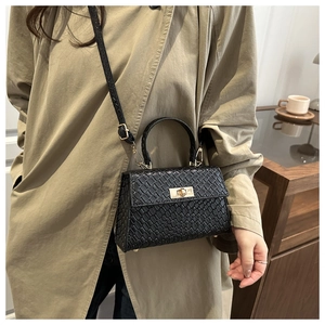 Detail of black woven texture handbag with gold twist lock and khaki trench coat outfit