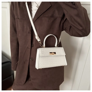 Gros plan d'un sac à main blanc à motif crocodile avec fermoir rotatif en métal doré