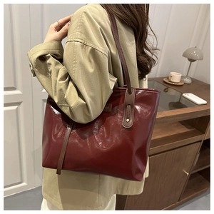 Detail of burgundy tote bag with glossy finish and long brown leather shoulder strap