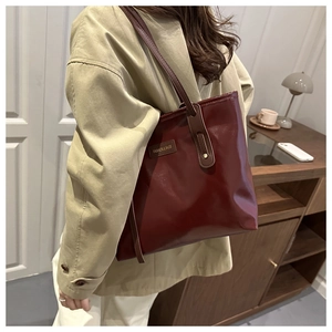 Deep red vintage leather tote bag shown on a model in a warm home interior setting