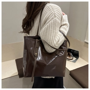 Close-up of deep brown glossy patent leather tote bag with slim shoulder straps
