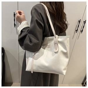 Detailed side view of white glossy large tote bag worn by a model in a minimalist room