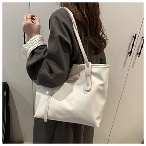 Detail of white glossy patent leather tote bag with Fashion & Bags logo plaque