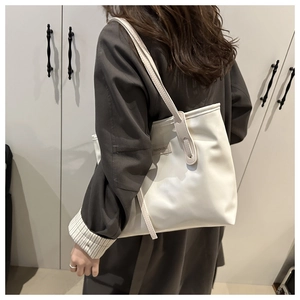 Side view of white minimalist tote bag with thin shoulder straps and fashion tag detail