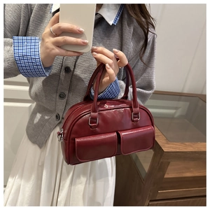 Detail of dark red faux leather bowling bag with twin flap pockets and smooth zipper