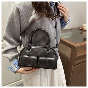 Detail view of a vintage dark grey crossbody bag with dual front pockets and top handles