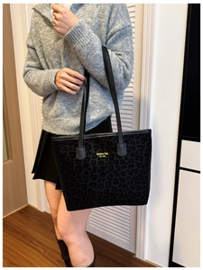 Detail view of leopard print tote bag with gold lettering and black shoulder straps