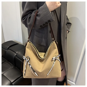 Detail of khaki tote bag featuring striped ribbon bows and brown leather straps