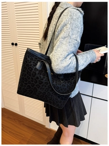 Close-up of leopard pattern texture and metal details on black tote shoulder bag