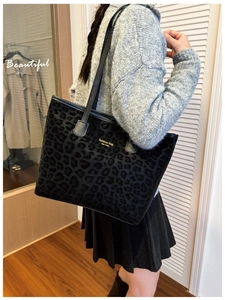 Detailed close-up of leopard print tote bag with gold lettering and leather handle