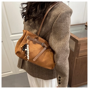 Close-up of brown suede tote bag featuring retro wooden beads and metal buckle detail