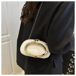 Close-up of white pebble leather mini bag with gold hardware worn on shoulder
