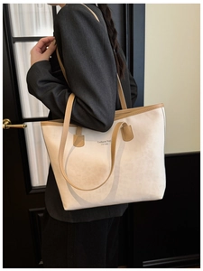 Detail of off-white tote bag with brown leather trim and New York text on a model