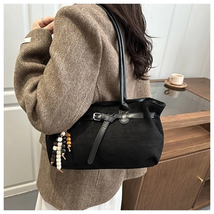 Detail of black suede tote bag with metal buckle and decorative tri-color wooden beads