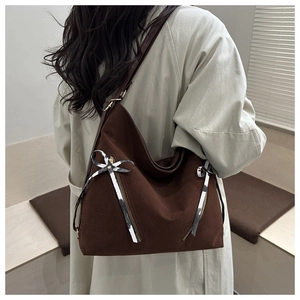 Close-up of brown suede tote bag with stylish black and white striped bow decorations