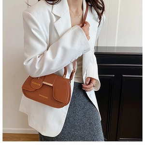 Détail d'un sac selle marron vintage avec boucle en métal et logo de mode gravé