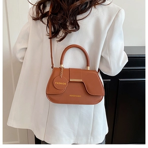 Caramel saddle bag with top handle and Fashion tag shown on white suit model