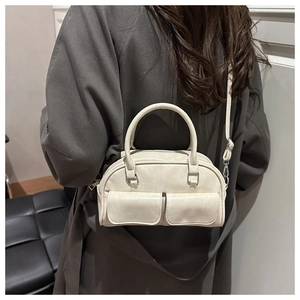 Close-up of a cream Boston bowling bag featuring dual front pockets and adjustable strap