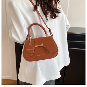 Close-up of a brown saddle bag featuring gold metal hardware and a round fashion tag