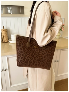 Brown leopard print tote bag with gold lettering shown in a cozy indoor setting