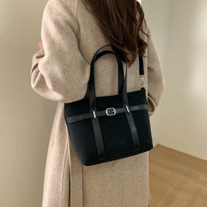 Large black tweed tote bag with leather handles shown on model in minimal indoor setting