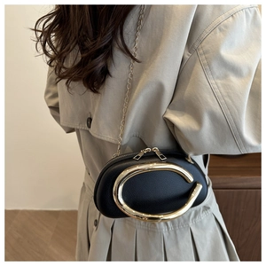 Detail of black pebbled leather crossbody bag with oversized gold horseshoe hardware