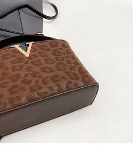 Detail of leopard print faux fur and smooth leather texture with gold V-shaped metal logo